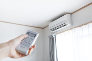 woman turning on a ductless mini split with a remote