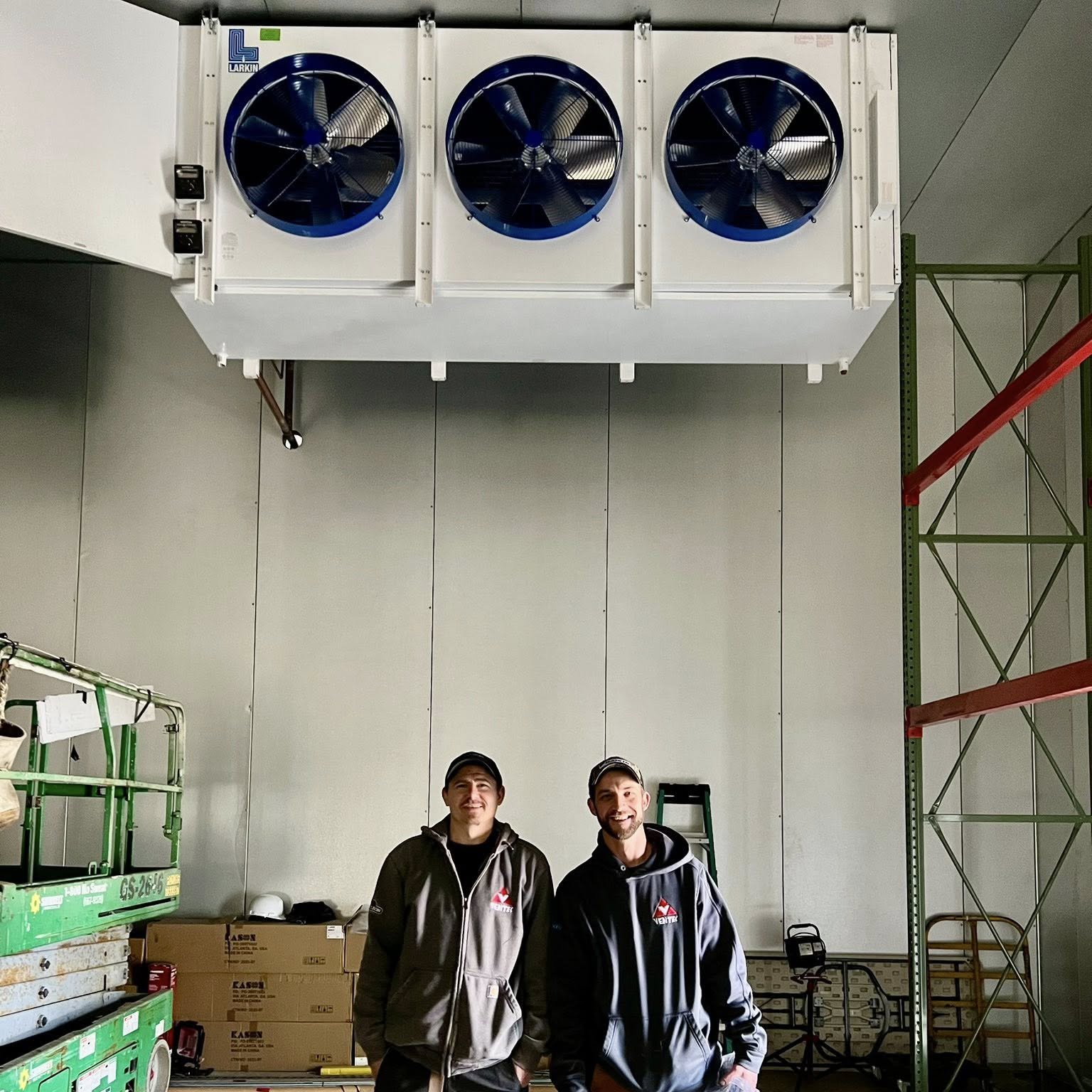 industrial evaporator unit in a cold storage warehouse installed by Ventec technicians seen below smiling