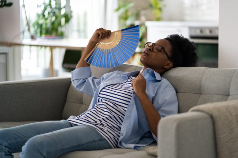 woman using handheld fan because her HVAC equipment is not adequate